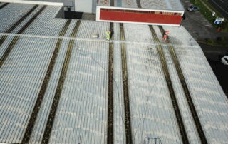 Technician performing commercial roof washing, removing moss, algae, and dirt from a large commercial property.