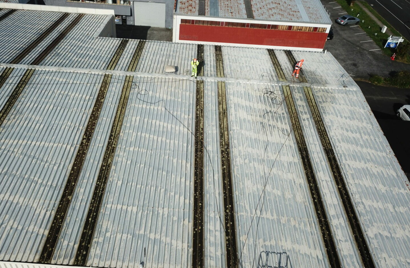 Technician performing commercial roof washing, removing moss, algae, and dirt from a large commercial property.