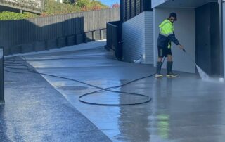 Concrete driveway being cleaned by Metro Water Blasting, removing dirt, moss, and stains.