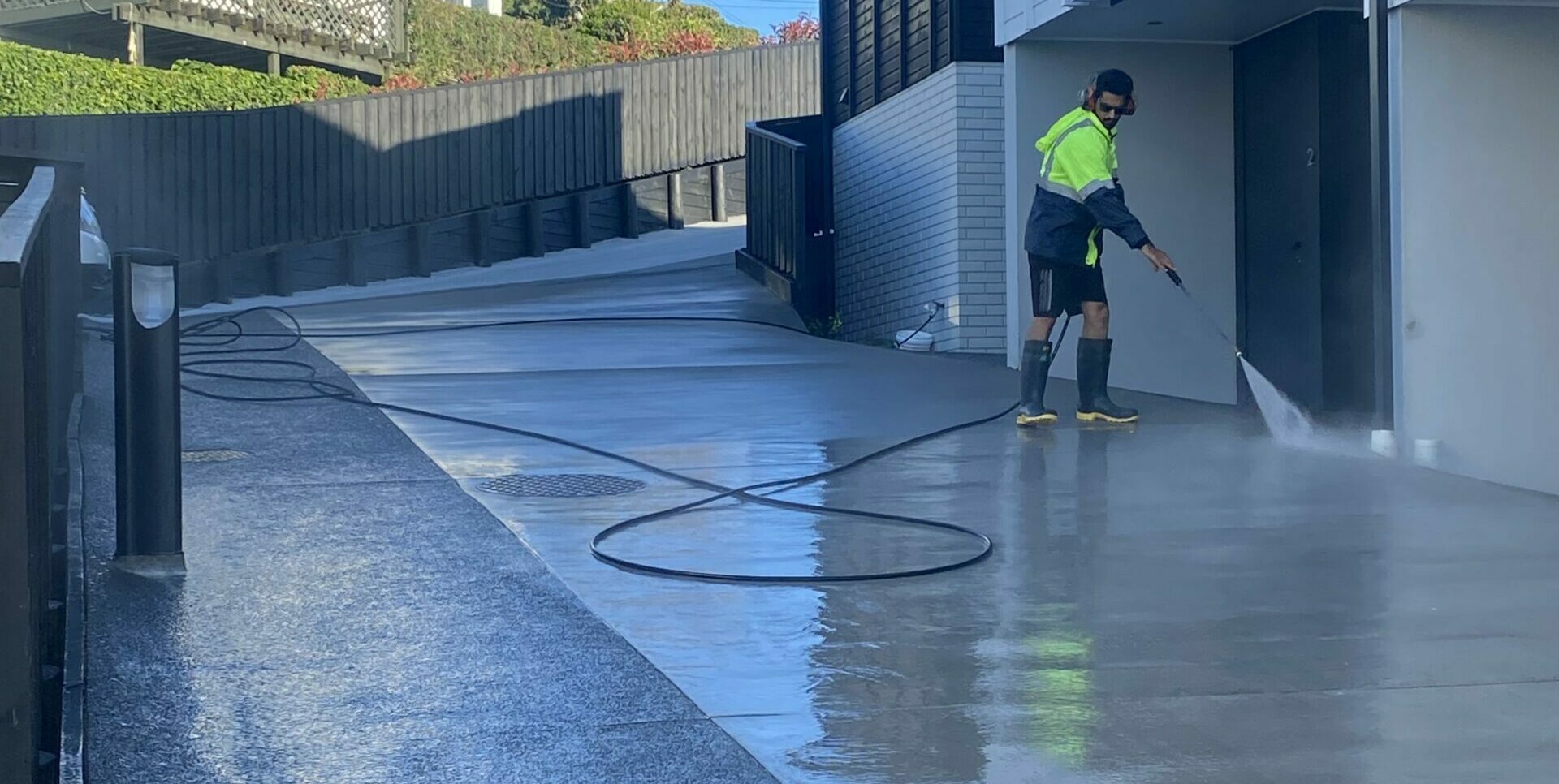 Concrete driveway being cleaned by Metro Water Blasting, removing dirt, moss, and stains.