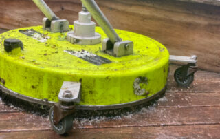 Technician using a machine to clean a deck, removing dirt and stains with powerful cleaning equipment.