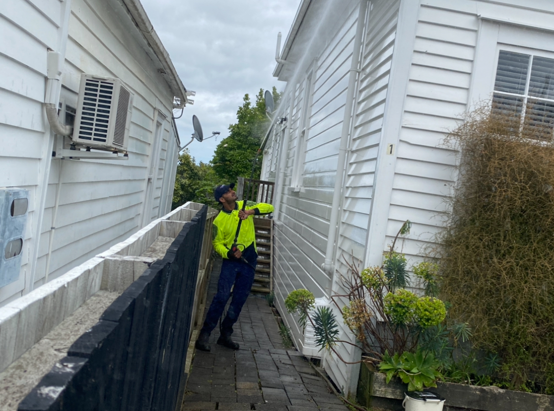 Metro Water Blasting technician performing soft washing on a house exterior to remove dirt, mold, and grime.