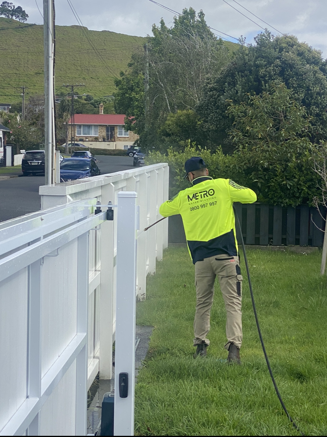 Metro Water Blasting technician cleaning a wooden fence, removing dirt, moss, and stains to restore the wood’s natural appearance.