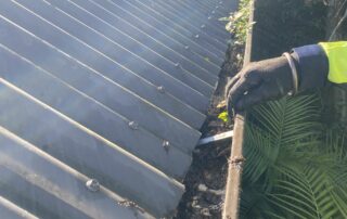 Metro Water Blasting technician hand-removing debris from residential gutters during cleaning service.