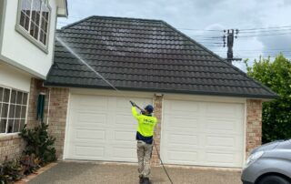Metro Water Blasting technician spraying moss and mould treatment onto a residential roof.