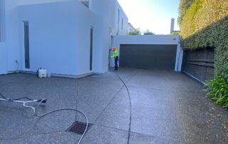Metro Water Blasting technician cleaning a concrete driveway with high-pressure water blasting.