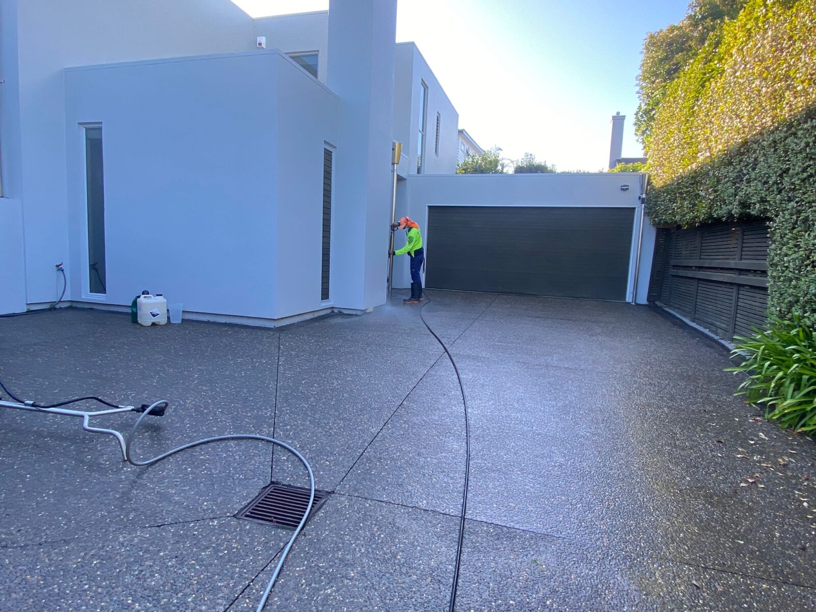 Metro Water Blasting technician cleaning a concrete driveway with high-pressure water blasting.