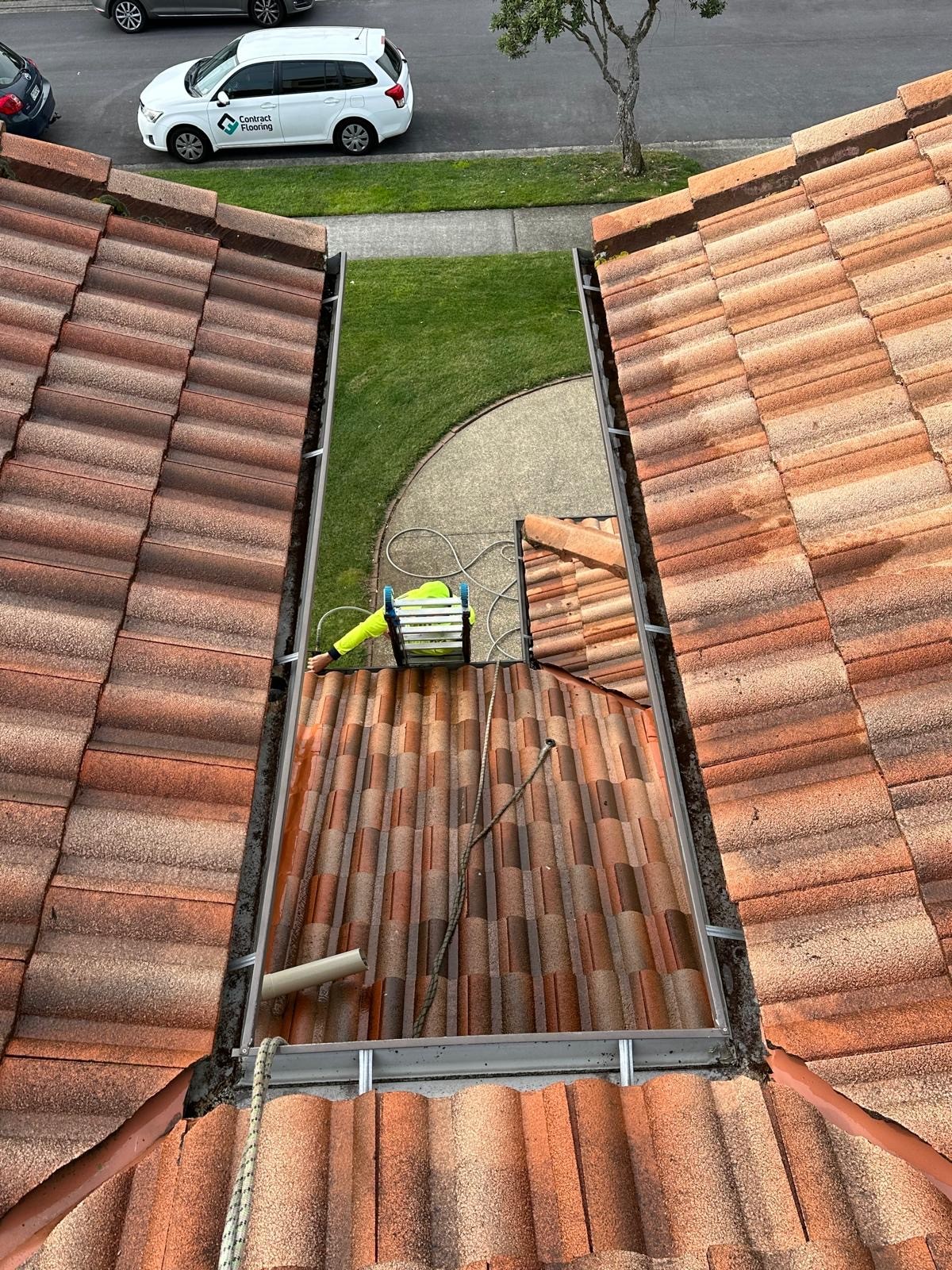 Technician on-site cleaning gutters and removing debris during professional service.